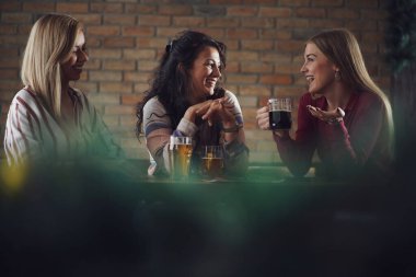 Üç mutlu kız arkadaş barda eğleniyor. Konuşuyorlar ve bira içiyorlar. Arkadaşlık kavramı.