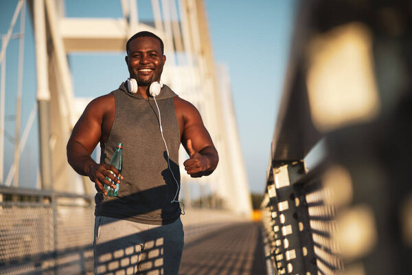 Портрет молодого веселого афроамериканца в спортивной одежде, смотрящего в камеру и улыбающегося. Он упражняется, чтобы уменьшить свой вес тела.