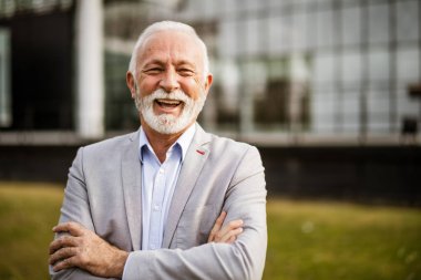 Şirket binasının önündeki neşeli kıdemli işadamının açık hava portresi..