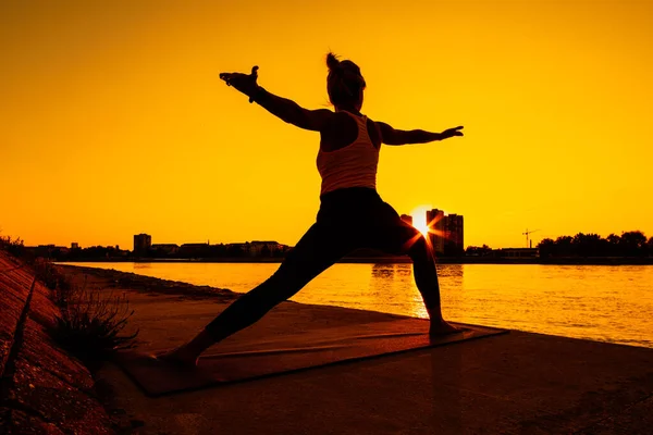 年轻女子正在户外运动 她在阳光灿烂的日子里练习瑜伽 Virabhadrasana Warrior 2姿势 — 图库照片