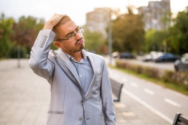 Sokakta durup düşünen hayal kırıklığına uğramış genç işadamının portresi. İşten sonra endişeli ve düşünceli bir iş adamı..