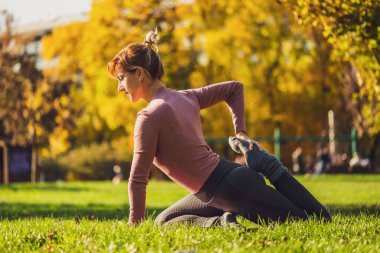 Sonbaharda parkta pilates yapan yetişkin bir kadın. Sağlıklı yaşam tarzı.