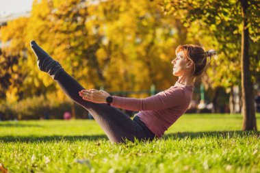Sonbaharda parkta pilates yapan yetişkin bir kadın. Sağlıklı bir yaşam tarzı. Teaser egzersizi.