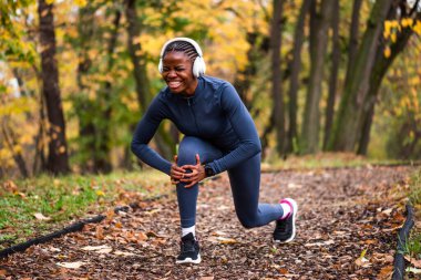 Genç siyah kadın sonbaharda parkta koşuyor ve yaralandı. Dizinde ağrı var.. 
