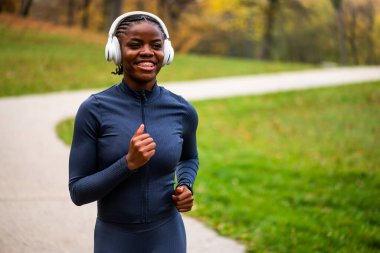 Gülümseyen bir koşucu şehir parkında koşuyor.