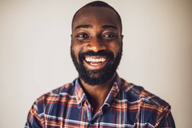 Kapalı tişörtlü, gülümseyen ve kameraya bakan mutlu siyah adamın portresi..