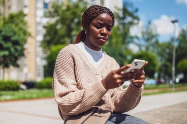 Huysuz Afrikalı Amerikalı kadın internet mesajlaşması için akıllı telefon kullanırken endişeli..