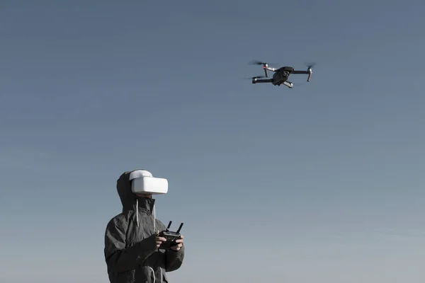 Turist yeni yerler keşfediyor. Kuadkopterle doğada İHA pilotu. Göl kenarında dururken insansız hava aracı kullanmak. İnsansız hava aracı ve sanal gerçeklik izleyicisi olan genç kişi.