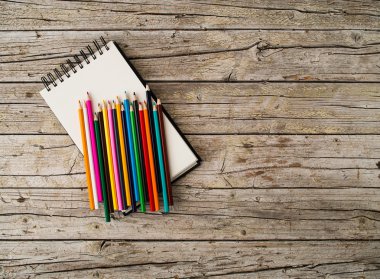 Renkli kurşun kalem boya kalemleri ve ahşap arka plan üstünde defter