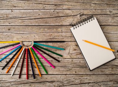 Renkli kurşun kalem boya kalemleri ve ahşap arka plan üstünde defter