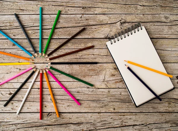 Renkli kurşun kalem boya kalemleri ve ahşap arka plan üstünde defter