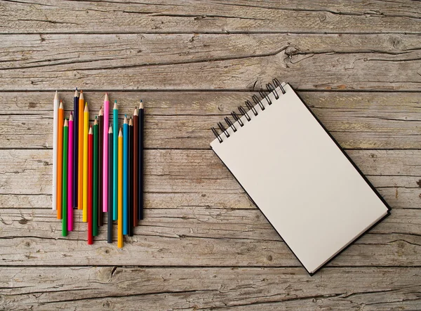 Lápiz de colores crayones y cuaderno sobre fondo de madera — Foto de Stock