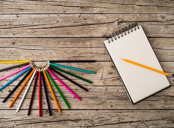 Lápiz de colores crayones y cuaderno sobre fondo de madera — Foto de Stock