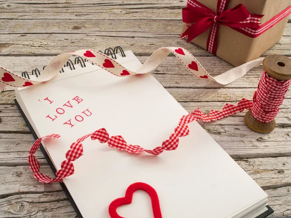 Gift, ribbon and notebook with I love you — Stock Photo, Image
