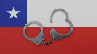 Yarı açık çelik kelepçeler ortada ve Şili bayrağının tepesinde.