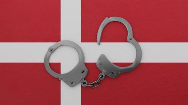 Yarı açık çelik kelepçeler ortada ve Danimarka bayrağının üstünde.