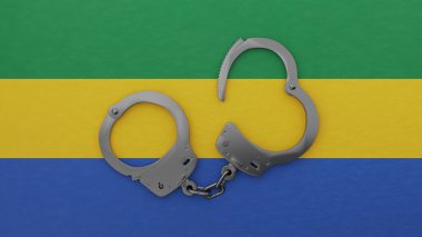 Yarı açık çelik kelepçe ortada ve Gabon bayrağının üstünde.