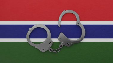 Yarı açık çelik kelepçe ortada ve Gambiya bayrağının üstünde.