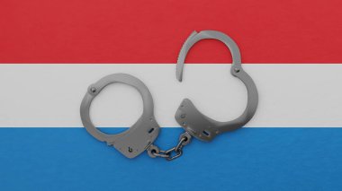 Yarı açık çelik kelepçeler ortada ve Lüksemburg bayrağının tepesinde.