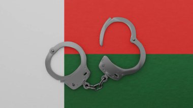 Yarı açık çelik kelepçeler ortada ve Madagaskar bayrağının tepesinde.