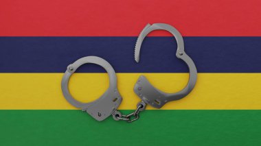 Yarı açık çelik kelepçe ortada ve Mauritius bayrağının üstünde.