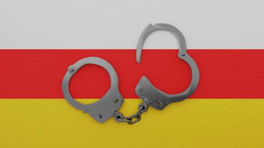 Yarı açık çelik kelepçeler ortada ve Güney Osetya bayrağının üstünde.