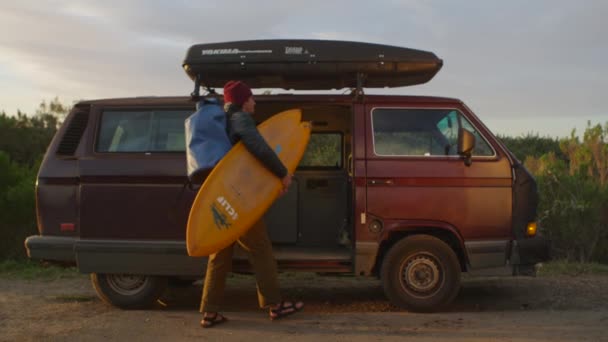 Un surfista saca su equipo de su caravana — Vídeo de stock