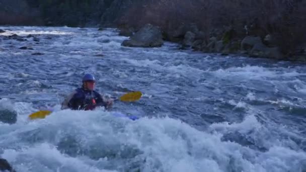 Een kayaker paddels via white water rapids — Stockvideo