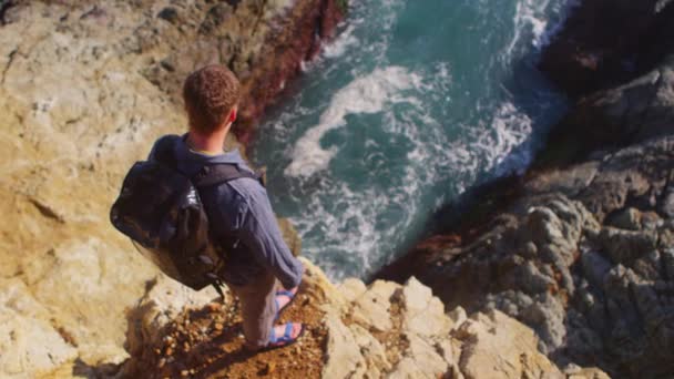 Man kijkt neer op de oceaan vanaf het zeeklip — Stockvideo