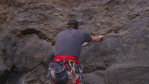 Un escalador escala una pared de roca pura — Vídeo de stock