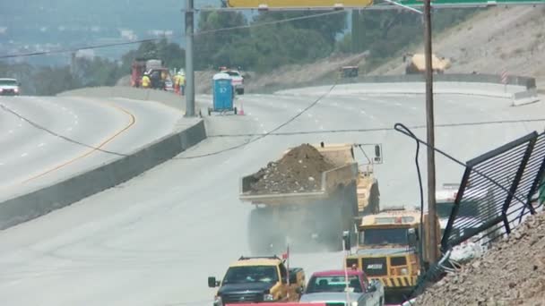 Los volquetes arrastran la tierra lejos de un tramo vacío en Los Ángeles mientras las tripulaciones derriban parte de un puente . — Vídeo de stock