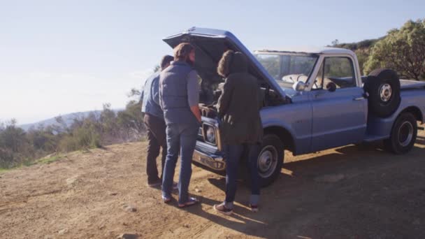 Amigos se paran alrededor de un camión con su capucha al lado de un camino rural — Vídeos de Stock