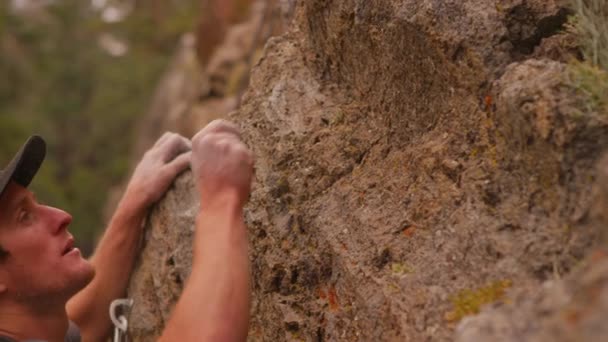 Скалолаз ударяет мелом с его пальцев, когда он взбирается на стену — стоковое видео