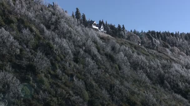 Casa en la parte superior de una ladera boscosa — Vídeos de Stock