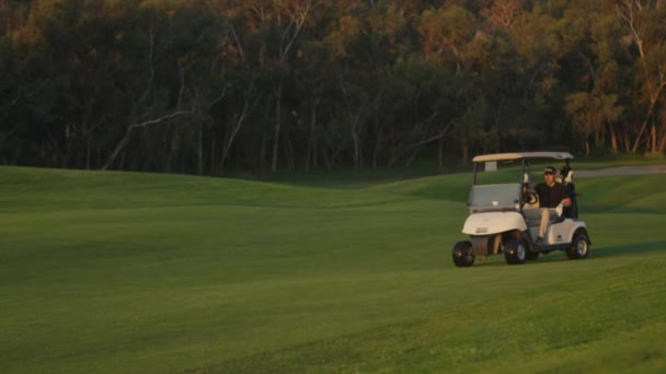 Golfistas passeio em um carrinho em um campo de golfe — Vídeo de Stock