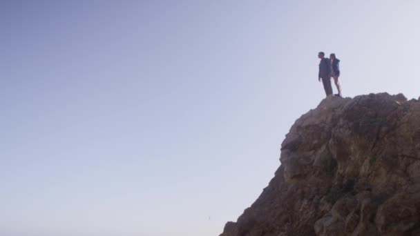 Пара, стоящая на вершине морской скалы — стоковое видео