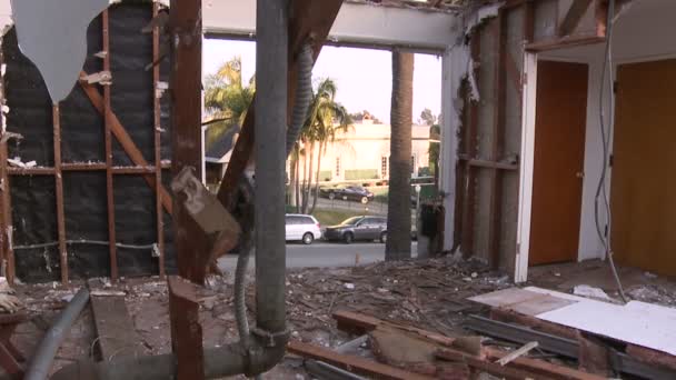 Autos fahren auf der Straße vor einem Haus vorbei, das gerade abgerissen wird — Stockvideo