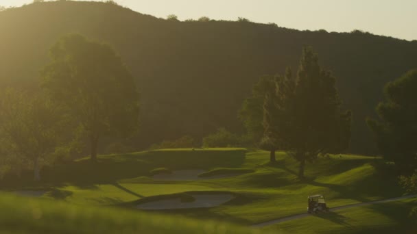 Carrito de golf viajando a lo largo de un campo de golf — Vídeo de stock