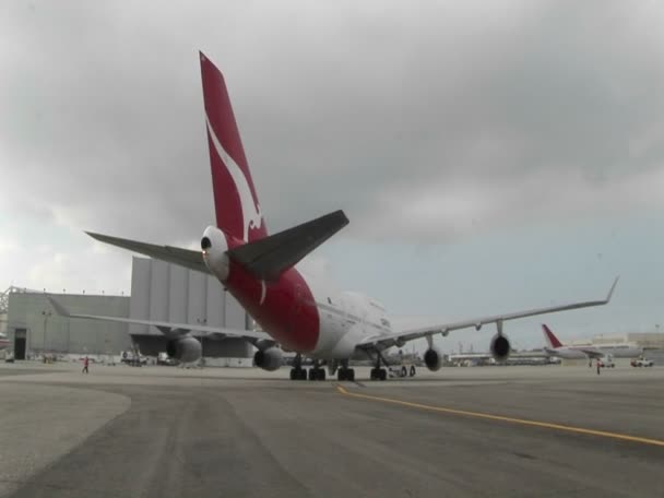 A Qantas 747 jet airplane is tugged on the ramp at an airport. — Stock Video