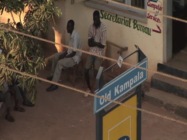 Мужчины сидят рядом с секретарским бюро в Кампале — стоковое видео