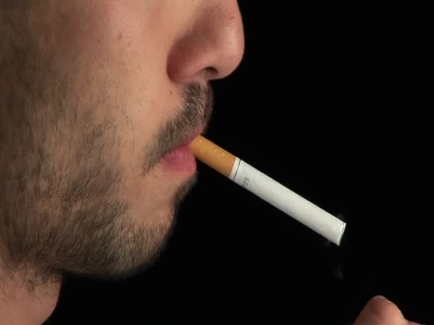 Un hombre enciende un cigarrillo de perfil y lo fuma — Vídeos de Stock