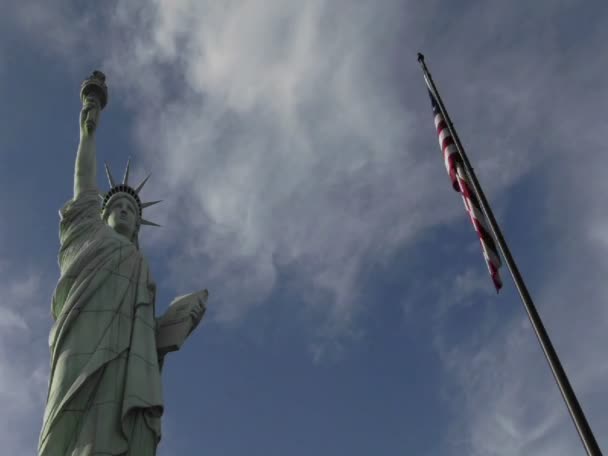 Nuvens movendo-se sobre a Estátua da Liberdade e bandeira americana — Vídeo de Stock