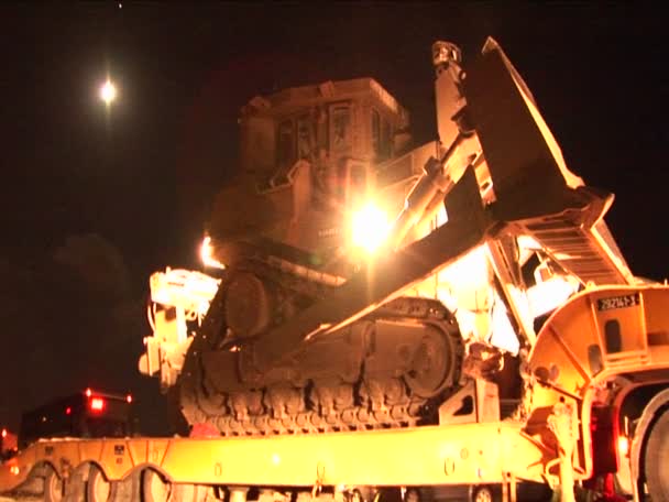 Um bulldozer blindado israelense é descarregado de um caminhão de mesa para patrulha noturna — Vídeo de Stock