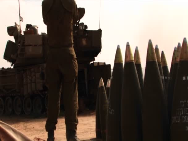 Израильский солдат стоит в стороне, как танк стреляет снарядами — стоковое видео