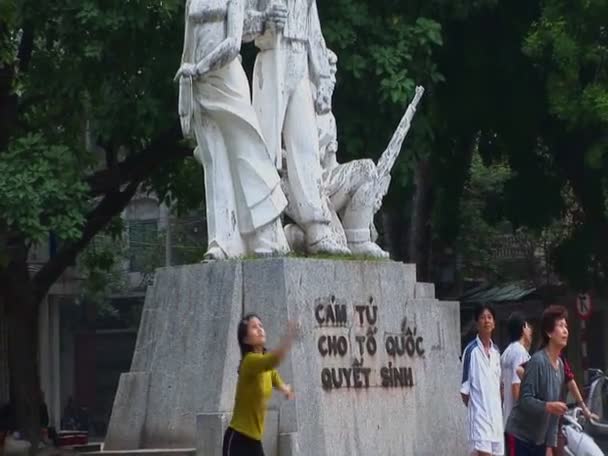 Bürger in Hanoi spielen Badminton vor einer öffentlichen Statue — Stockvideo