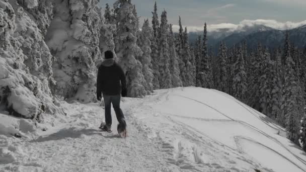 Un hombre raquetas de nieve a través de una montaña nevada — Vídeos de Stock