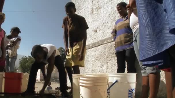 Mensen krijgen water uit een put na een enorme aardbeving — Stockvideo