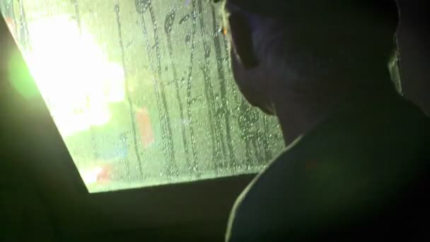 Een man kijkt door het raam van een boot — Stockvideo