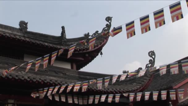 Banderas cuelgan de los aleros de un templo chino — Vídeo de stock