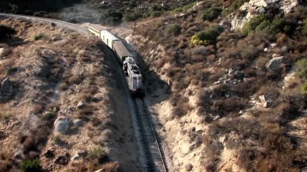 Een trein reist door een bergachtig gebied — Stockvideo